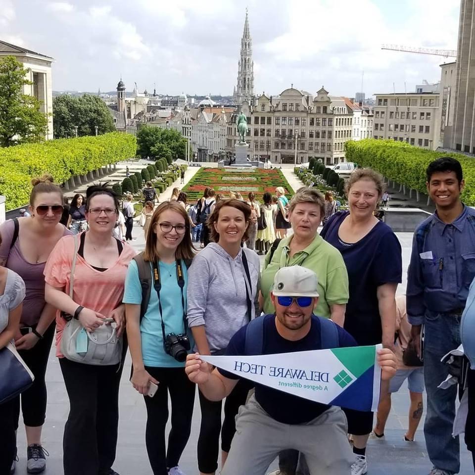 A group of students with a Delaware Tech Flag during their trip to Italy